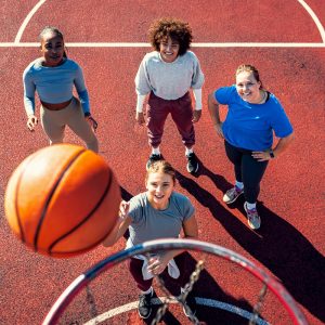 Portait of diverse group of young woman having fun playing basketball outdoors.