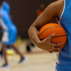 Diverse male basketball players wearing blue sports clothes and playing basketball at gym. Sport, activity, togetherness and lifestyle, unaltered, copy space.
