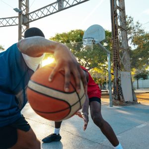 One vs one basketball game training at the court. Cinematic look image of friends practicing shots and slam dunks in an urban area