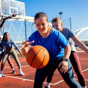 Diverse group of young woman having fun playing recreational basketball outdoors.